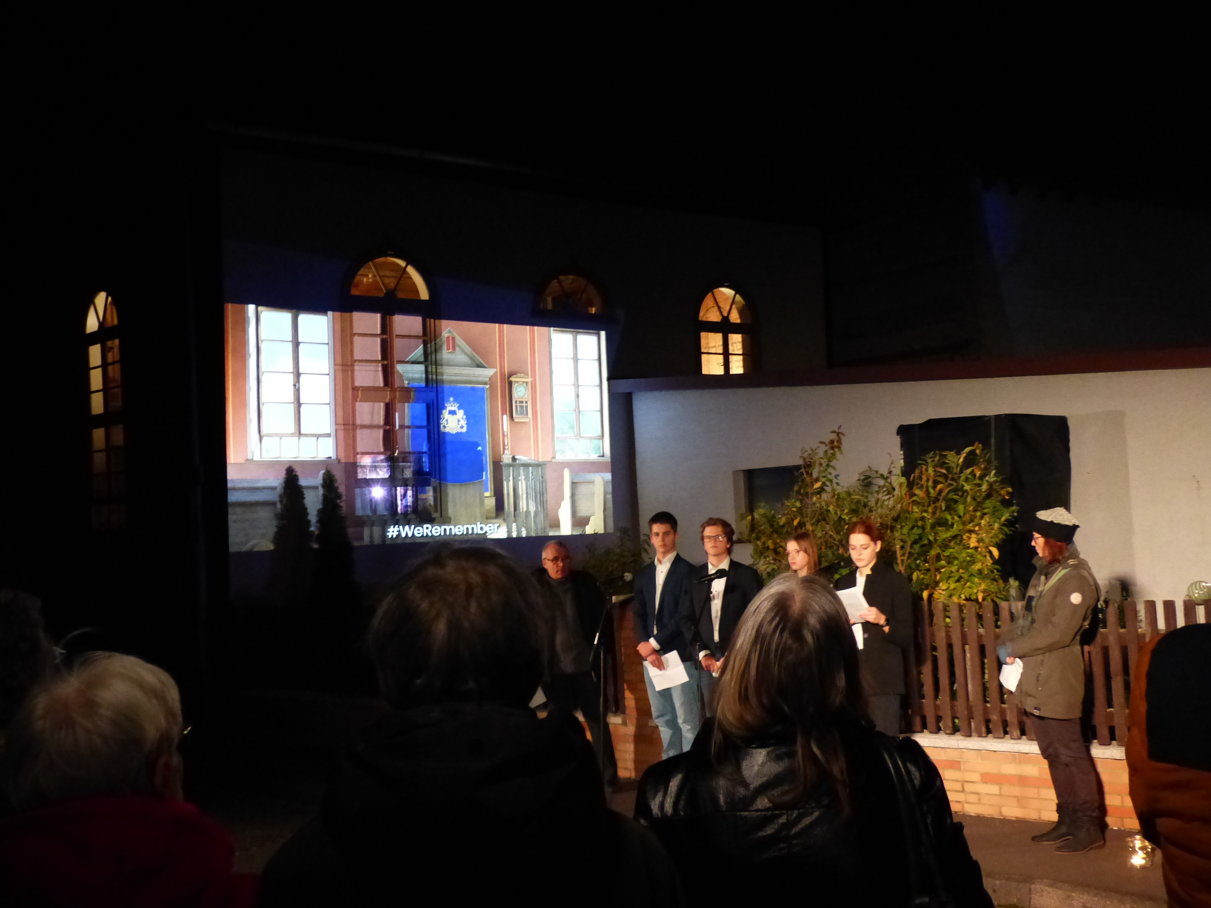 Eine Gruppe von Menschen am Abend vor der beleuchteten Synagoge